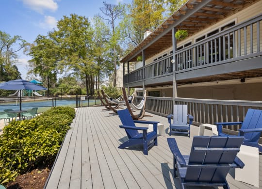a deck with blue chairs and a house with a pool
