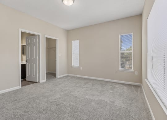 an empty living room with white blinds and a door to a bathroom