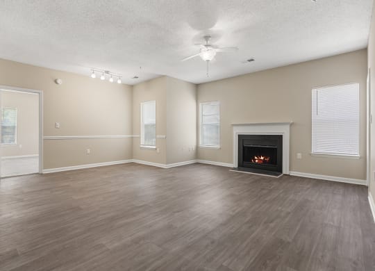 an empty living room with a fireplace and a ceiling fan