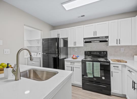 a white kitchen with black appliances and a sink