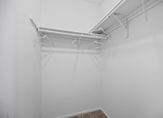 an empty closet with white walls and white pipes on the ceiling
