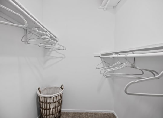 a walk in closet with white walls and a basket in the corner