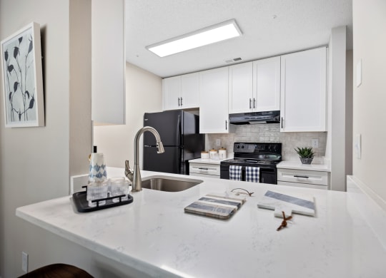 an open kitchen with white cabinets and a white counter top with a sink and stove