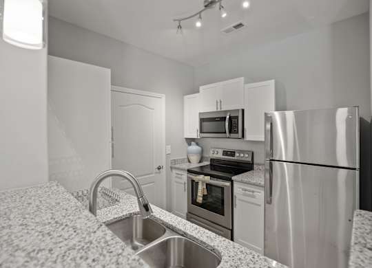 A kitchen with a sink, stove, and refrigerator.