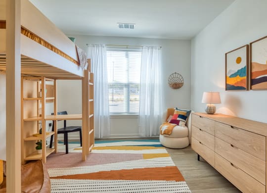 a bedroom with bunk beds and a desk and a window