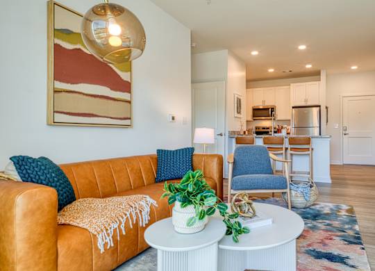 a living room with a couch and a table in front of a kitchen