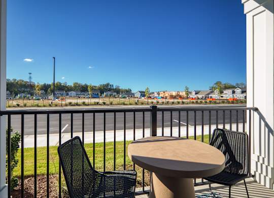 a balcony with a table and chairs and a view of a parking lot