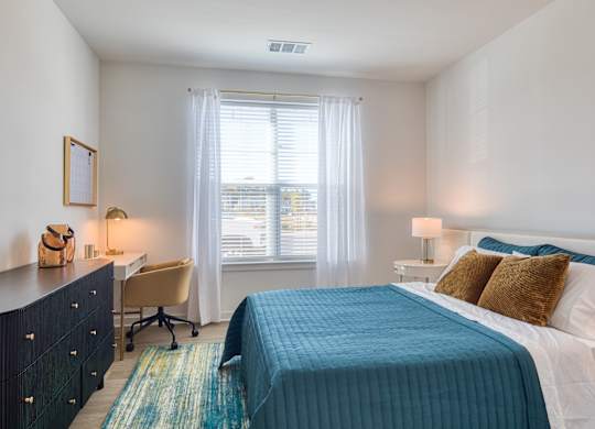 a bedroom with a bed and a desk and a window