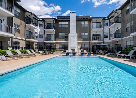 A large swimming pool in front of apartment buildings.