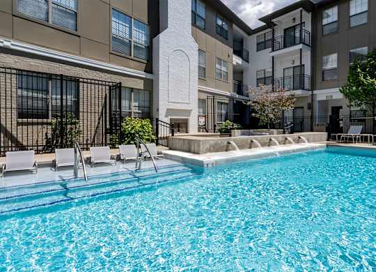 A swimming pool in front of a building with a white pillar.