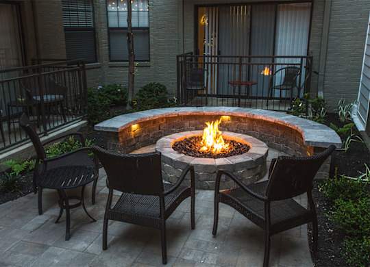 A fire pit in the middle of a patio surrounded by chairs.