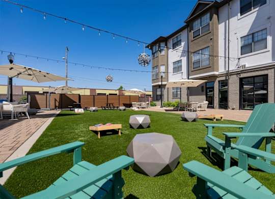 A sunny day at the outdoor seating area of a building with green chairs and tables.