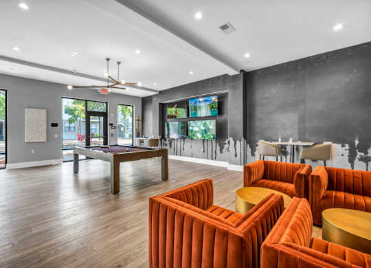 A living room with orange chairs and a wooden floor.