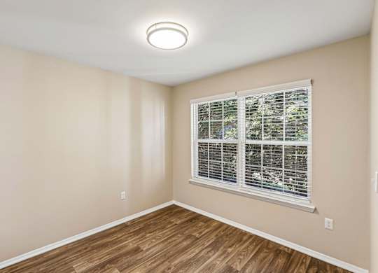 A room with a window and wooden flooring.