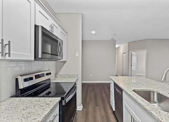 A kitchen with granite countertops and white cabinets.