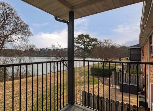 A balcony with a black railing overlooks a body of water.