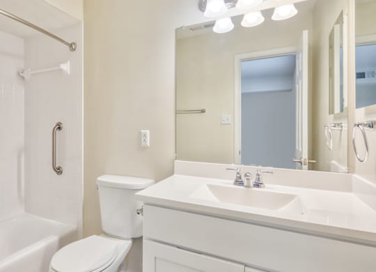A white bathroom with a toilet, sink, and shower.