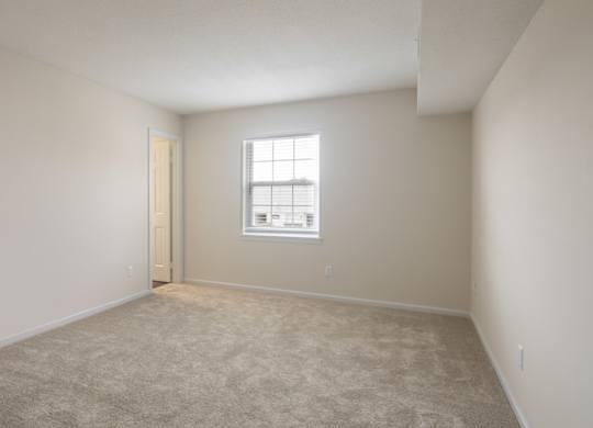 A room with a carpeted floor and a window.