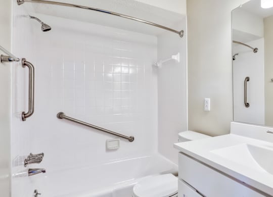 A white bathroom with a sink, mirror, and shower.