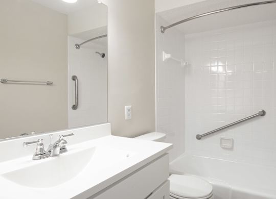 A white bathroom with a toilet, sink, and shower.