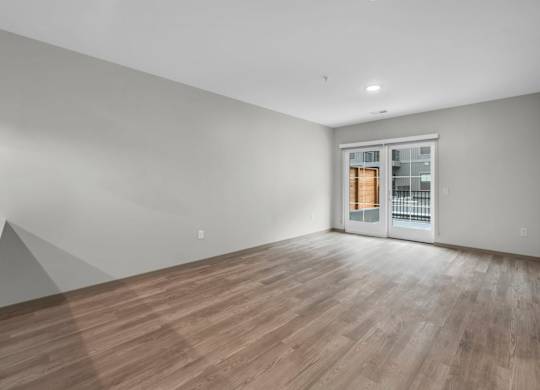 A room with wooden flooring and a white door with a glass panel.