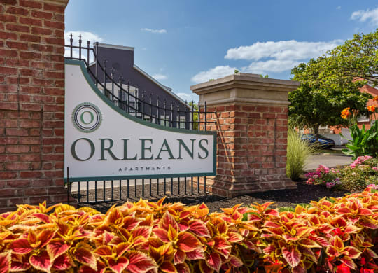 the sign for orleans apartments in front of a gate and flowers at Orleans Apartments, Columbus, 43221