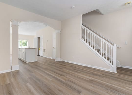 an empty living room with a staircase and a kitchen at Orleans Apartments, Columbus, Ohio