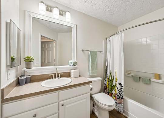 A white bathroom with a sink, toilet, and shower.