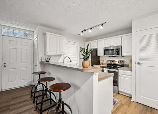 A kitchen with white cabinets and a white island with a plant on top.