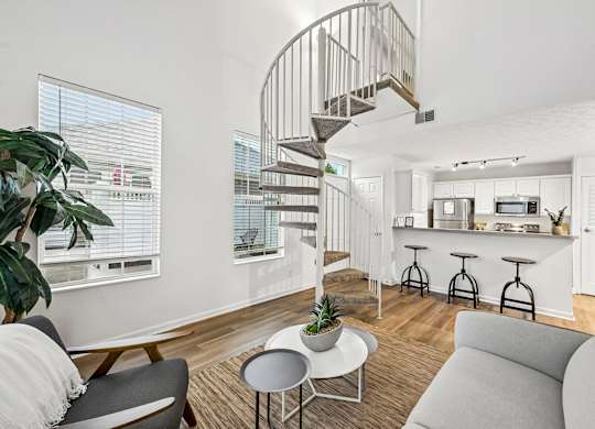 A living room with a spiral staircase and a grey couch.