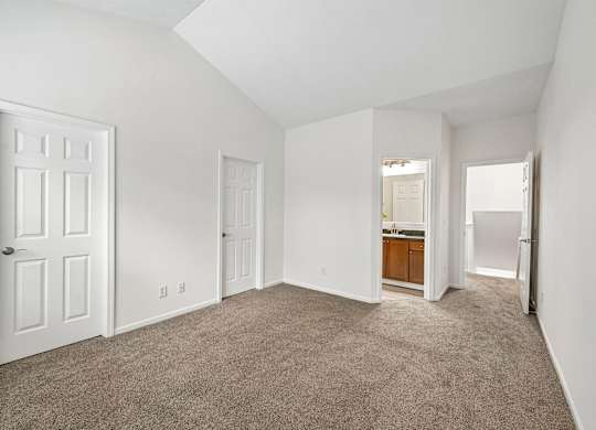 A spacious room with white walls and carpeted floor.
