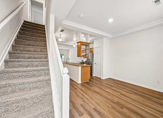 A staircase with a carpeted runner leads up to a landing with a wooden cabinet and a door.