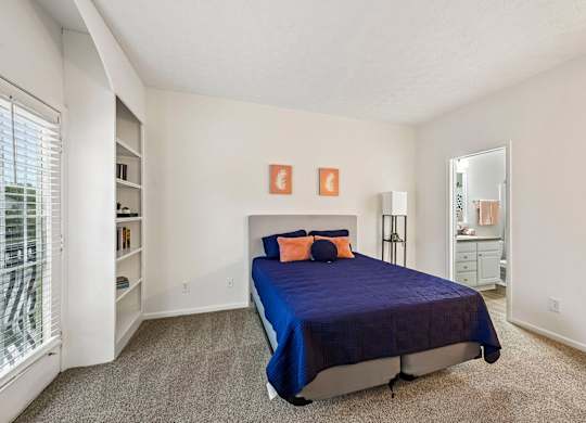 A bedroom with a bed, dresser, and window.