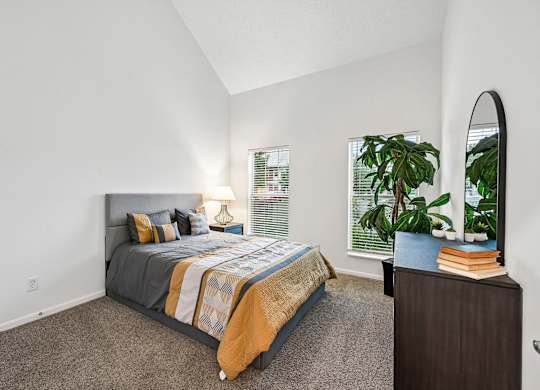 A bedroom with a bed, nightstand, and a potted plant.