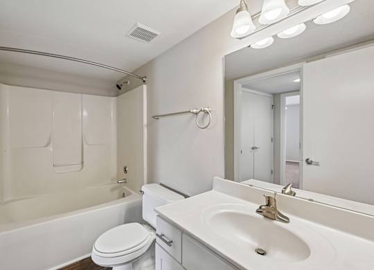 A white bathroom with a toilet, sink, and mirror.