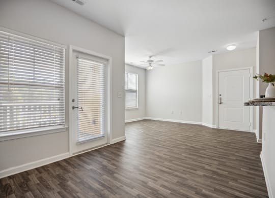 an empty living room and dining room with white walls and wood flooring
