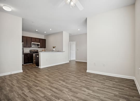 an empty living room and kitchen with white walls and wood flooring