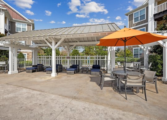 a patio with an umbrella and tables and chairs