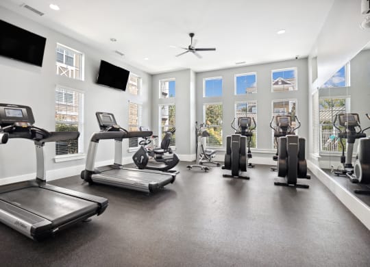 the gym with treadmills and other exercise equipment in a building with windows