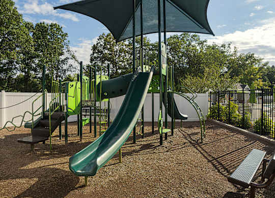 A playground with a green slide and a bench.