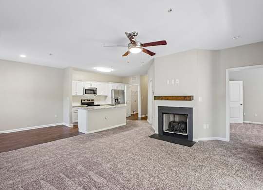 A spacious living room with a fireplace and a ceiling fan.