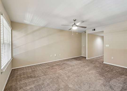 A room with a ceiling fan and carpeted floor.