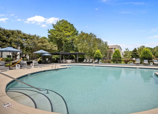 a swimming pool with trees in the background and a blue sky