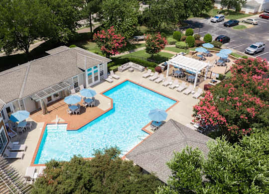 A large swimming pool surrounded by trees and a building.