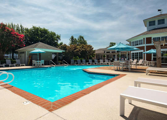 A swimming pool with a white bench and a blue umbrella.