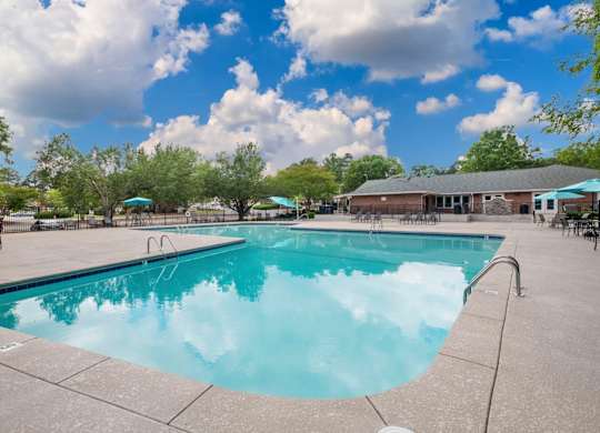 A large swimming pool with a blue tinted water and a cloudy sky in the background.