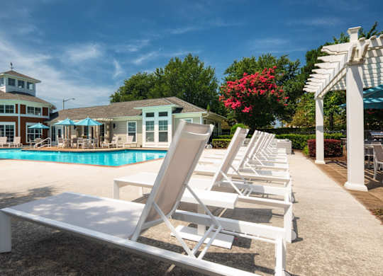 A poolside area with sun loungers and a building in the background.