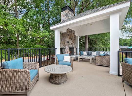 A patio with a white pergola and a stone pillar.