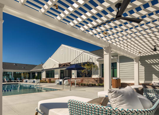 a patio with a pool and chairs under a pergola