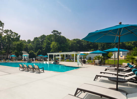 a swimming pool with lounge chairs and umbrellas
